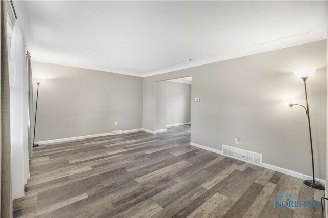 empty room with ornamental molding and dark wood-type flooring