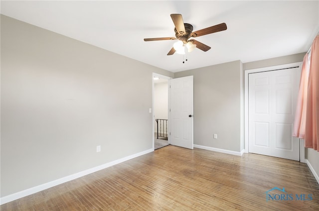 unfurnished bedroom featuring ceiling fan, light hardwood / wood-style floors, and a closet