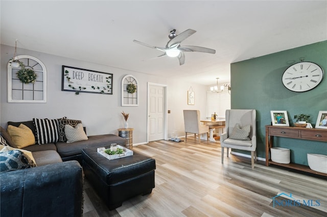 living room with wood-type flooring and ceiling fan with notable chandelier