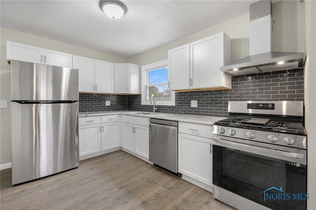 kitchen featuring white cabinetry, light hardwood / wood-style flooring, wall chimney exhaust hood, and appliances with stainless steel finishes