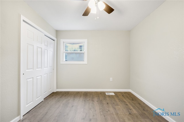 unfurnished bedroom featuring a closet, light hardwood / wood-style flooring, and ceiling fan