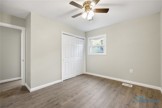 unfurnished bedroom featuring ceiling fan, a closet, and dark wood-type flooring