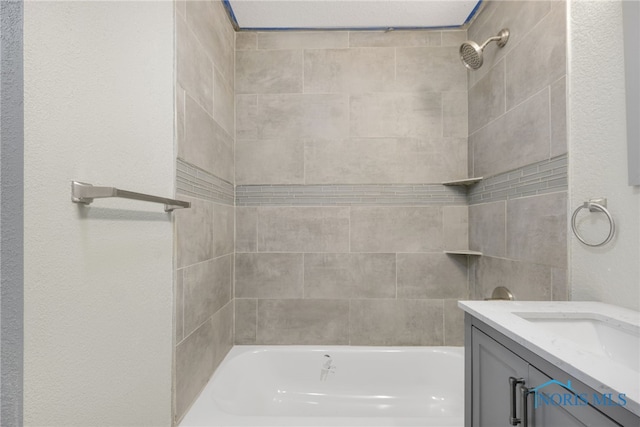 bathroom with tiled shower / bath combo and vanity