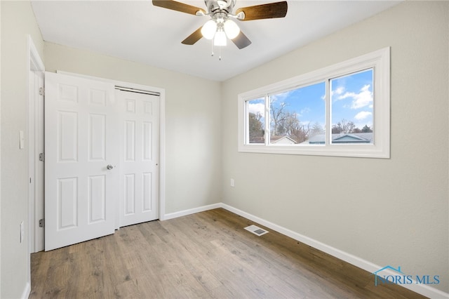 unfurnished bedroom featuring ceiling fan, light hardwood / wood-style floors, and a closet