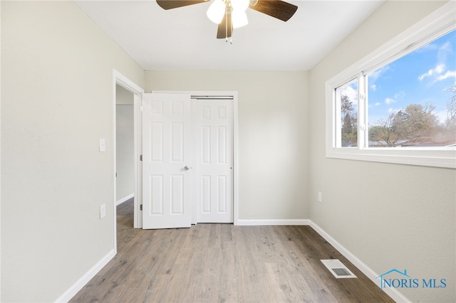 unfurnished bedroom featuring ceiling fan, light wood-type flooring, and a closet