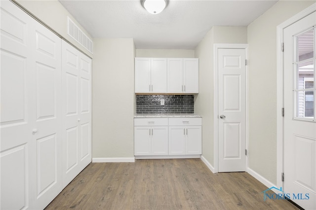 kitchen with decorative backsplash, white cabinets, and light hardwood / wood-style floors