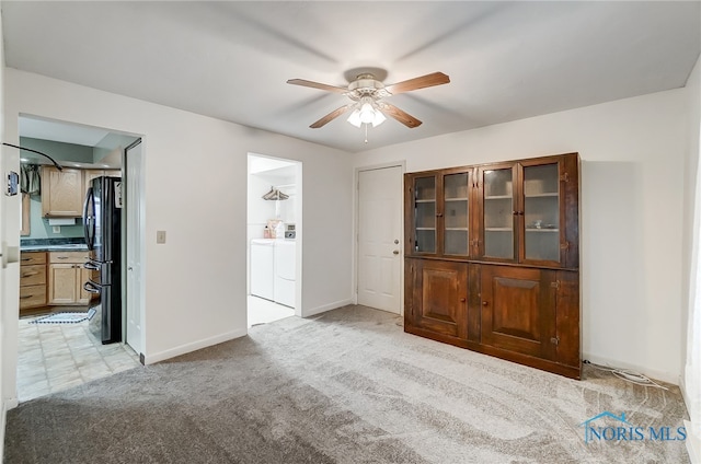 carpeted spare room featuring washer and dryer and ceiling fan