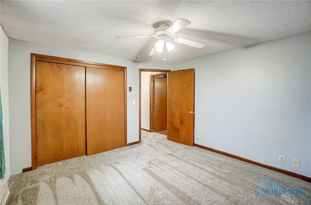 unfurnished bedroom featuring ceiling fan, a closet, light colored carpet, and a textured ceiling