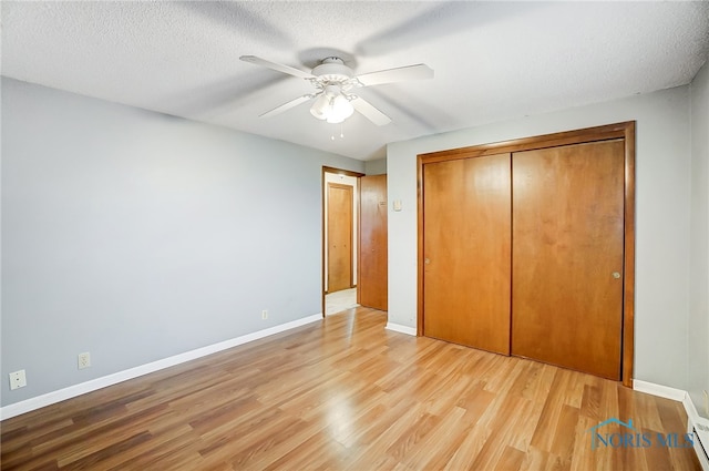 unfurnished bedroom featuring ceiling fan, a closet, a textured ceiling, and light hardwood / wood-style flooring