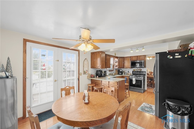 dining space featuring ceiling fan, sink, light wood-type flooring, and french doors