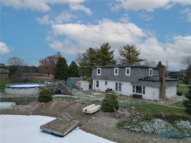 rear view of house featuring a swimming pool side deck and a shed