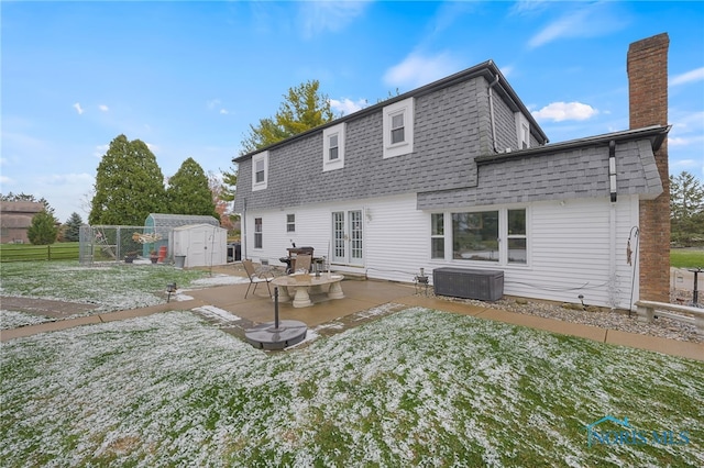 back of property with central AC unit, a lawn, a patio, and a storage unit