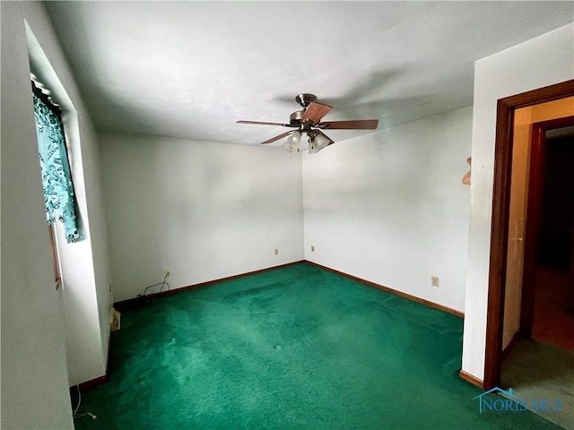 spare room featuring ceiling fan and dark colored carpet