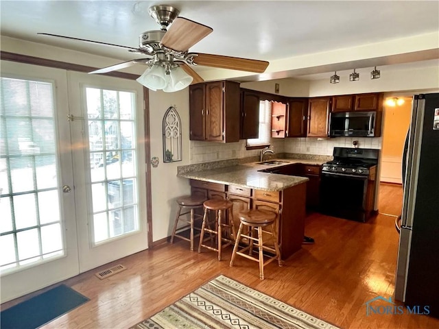 kitchen featuring a breakfast bar, tasteful backsplash, appliances with stainless steel finishes, dark hardwood / wood-style flooring, and kitchen peninsula