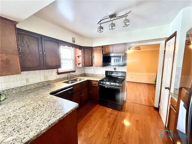 kitchen featuring sink, light hardwood / wood-style flooring, backsplash, light stone counters, and black appliances