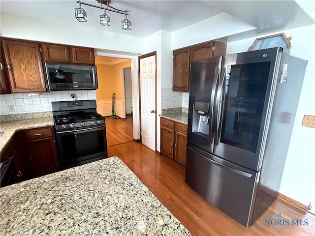 kitchen featuring light stone counters, backsplash, dark hardwood / wood-style floors, and appliances with stainless steel finishes