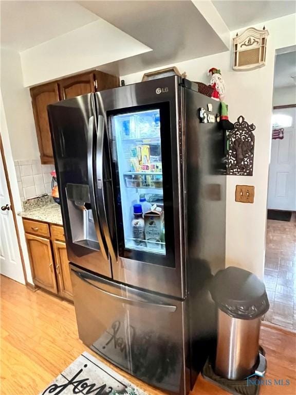 kitchen featuring tasteful backsplash, stainless steel fridge, and light hardwood / wood-style flooring