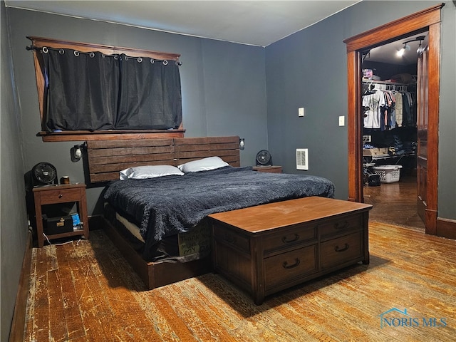 bedroom featuring a walk in closet, light hardwood / wood-style flooring, and a closet