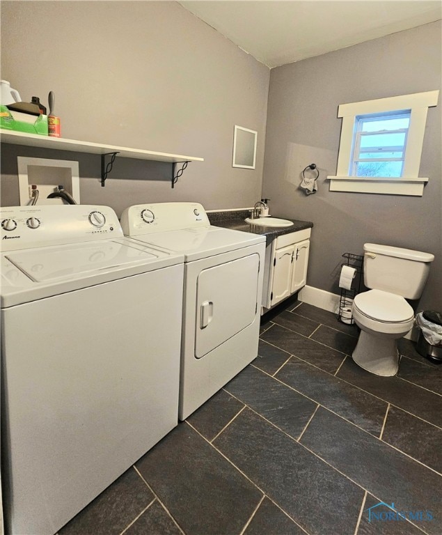 laundry room featuring dark tile patterned floors, sink, and washing machine and clothes dryer