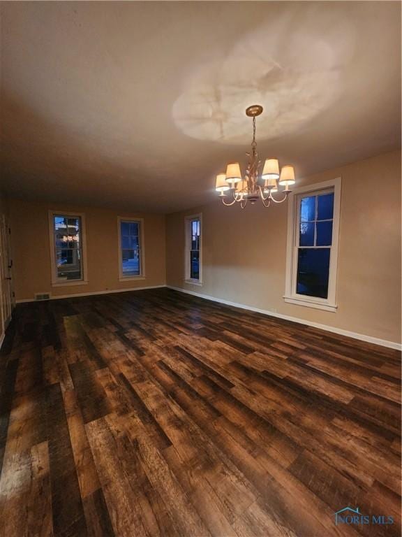 unfurnished room featuring a notable chandelier and dark hardwood / wood-style floors