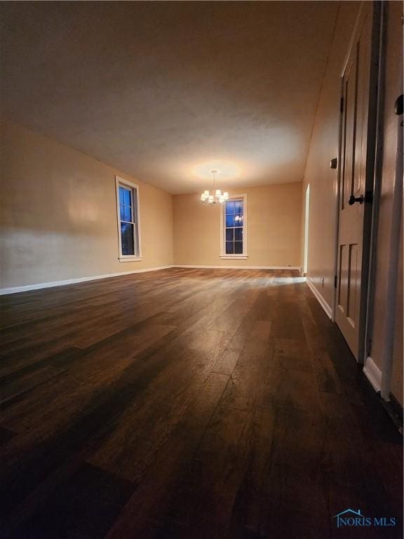 spare room with dark hardwood / wood-style flooring and a chandelier