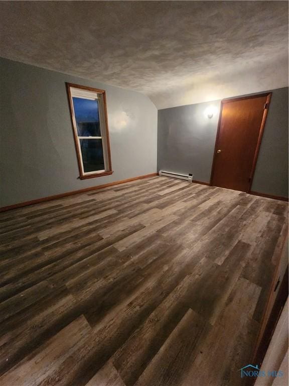 empty room with a textured ceiling, dark wood-type flooring, and a baseboard radiator