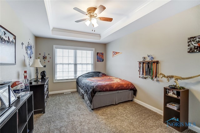 bedroom featuring light carpet, a tray ceiling, ceiling fan, and ornamental molding