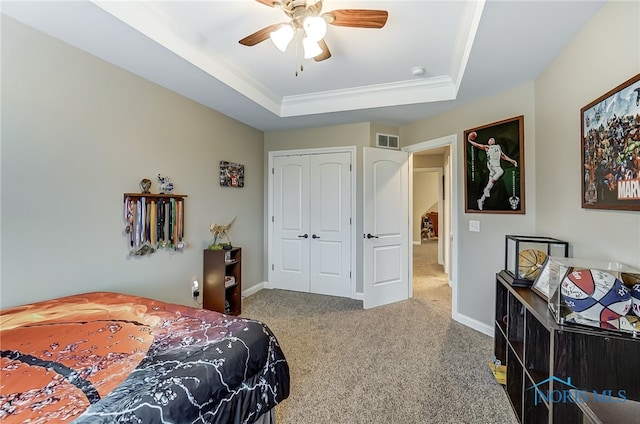 carpeted bedroom featuring ceiling fan, a tray ceiling, and a closet