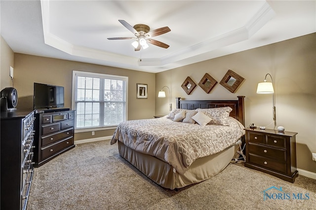 carpeted bedroom featuring a raised ceiling, ceiling fan, and ornamental molding