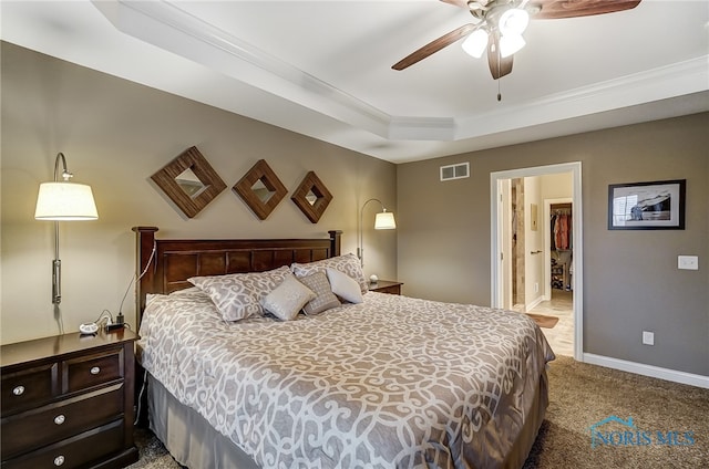 carpeted bedroom featuring ceiling fan and a raised ceiling