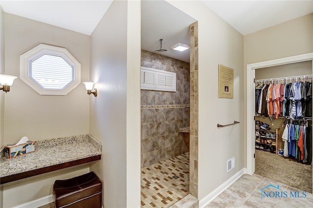 bathroom with a tile shower and tile patterned floors