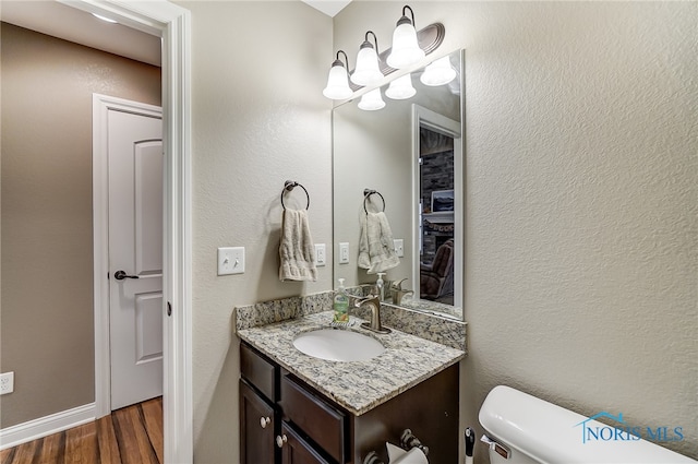 bathroom featuring vanity, wood-type flooring, and toilet