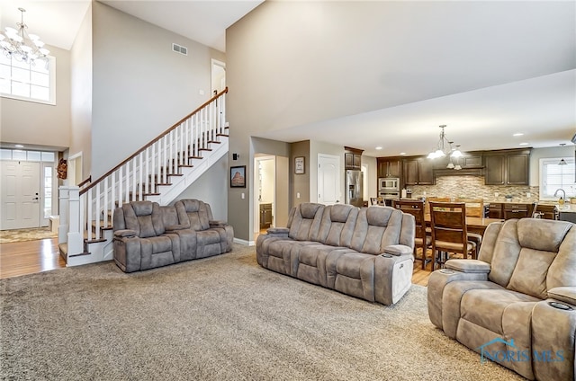 living room featuring a chandelier, high vaulted ceiling, and light hardwood / wood-style floors