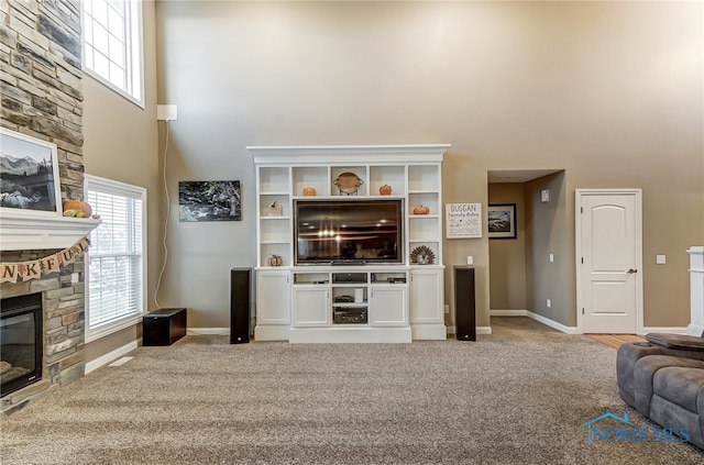 carpeted living room featuring a fireplace and a high ceiling