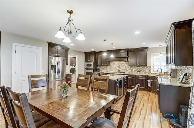 dining space with a chandelier, washer / dryer, light hardwood / wood-style floors, and sink