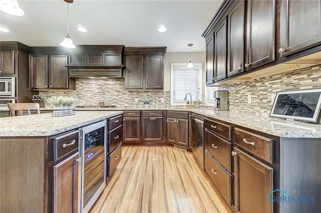 kitchen with wine cooler, dark brown cabinetry, light hardwood / wood-style floors, and decorative light fixtures