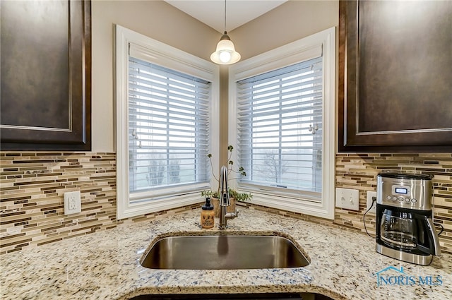 kitchen with a wealth of natural light, hanging light fixtures, and light stone countertops