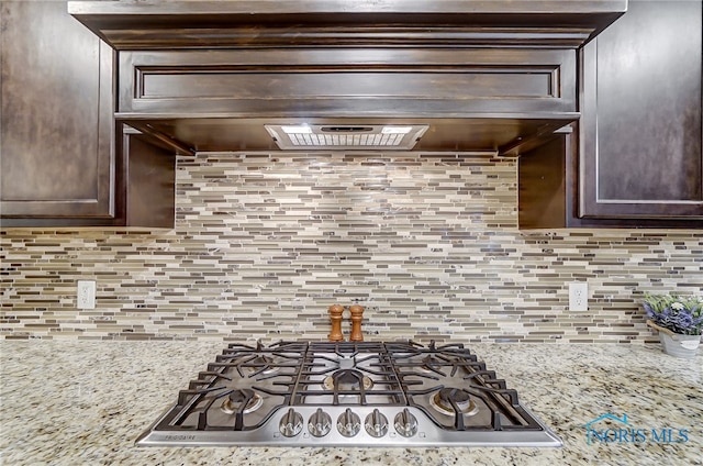 kitchen featuring light stone countertops, decorative backsplash, and dark brown cabinetry