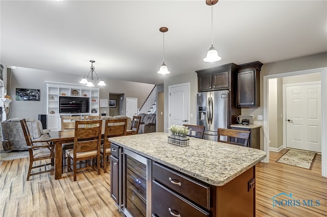 kitchen featuring wine cooler, stainless steel fridge, a kitchen island, and light wood-type flooring