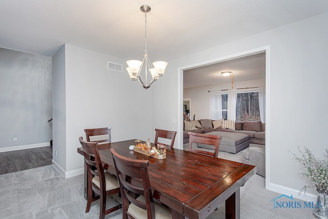 dining space with light carpet and a notable chandelier