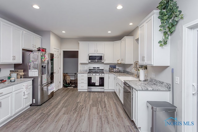 kitchen with hardwood / wood-style floors, white cabinets, sink, and stainless steel appliances