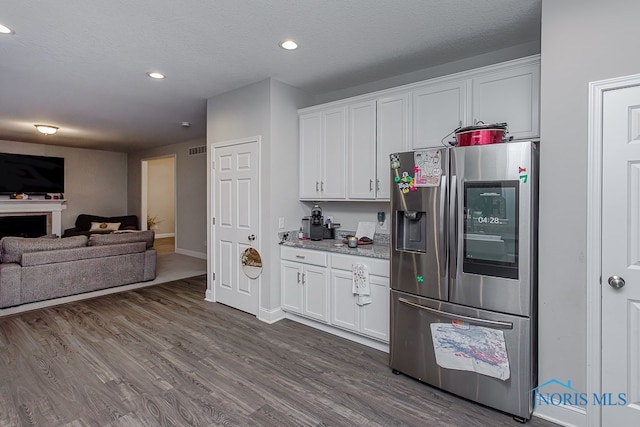 kitchen with stainless steel fridge with ice dispenser, dark hardwood / wood-style flooring, a textured ceiling, and white cabinetry