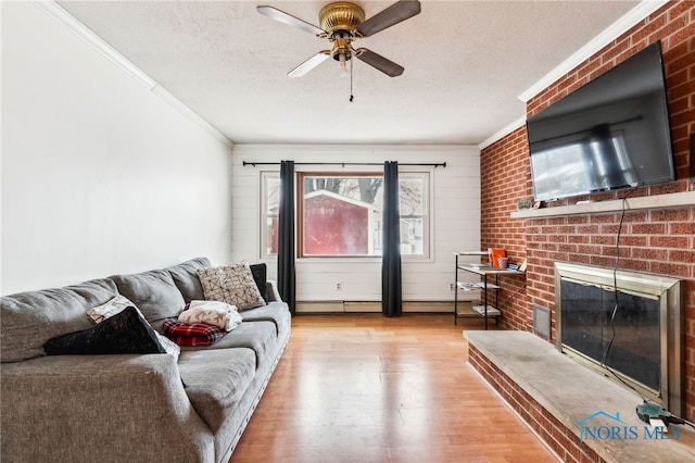 living room featuring a fireplace, crown molding, a textured ceiling, and light hardwood / wood-style flooring