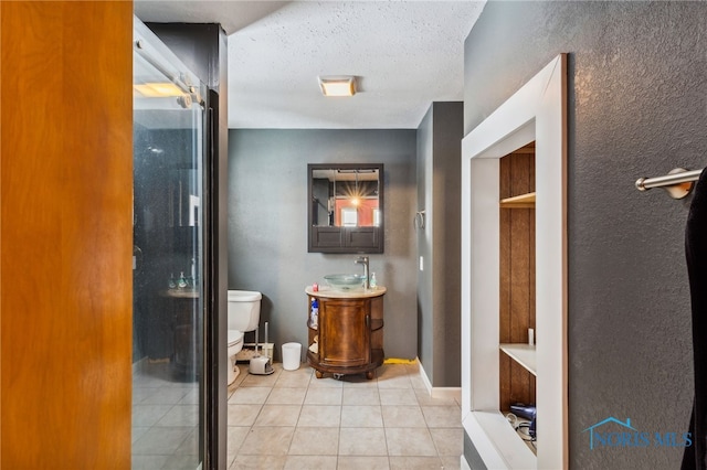 bathroom with vanity, a shower with door, tile patterned flooring, toilet, and a textured ceiling