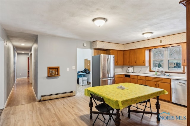 kitchen with sink, light hardwood / wood-style flooring, a baseboard radiator, and appliances with stainless steel finishes