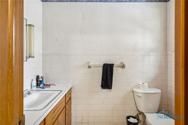 bathroom with vanity, tile walls, and toilet