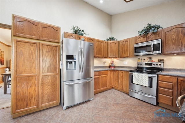 kitchen with light tile patterned floors, a high ceiling, and appliances with stainless steel finishes