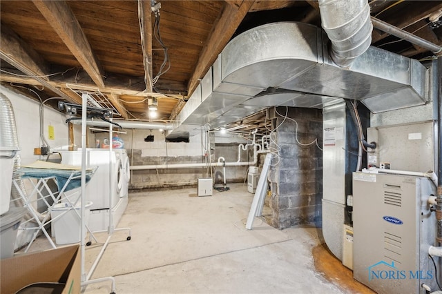 basement featuring heating unit and washing machine and clothes dryer