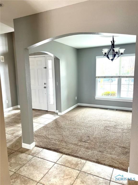 foyer with light tile patterned floors and an inviting chandelier