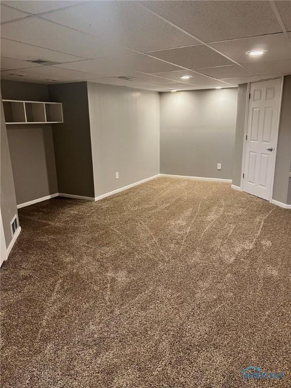 basement featuring dark carpet and a paneled ceiling